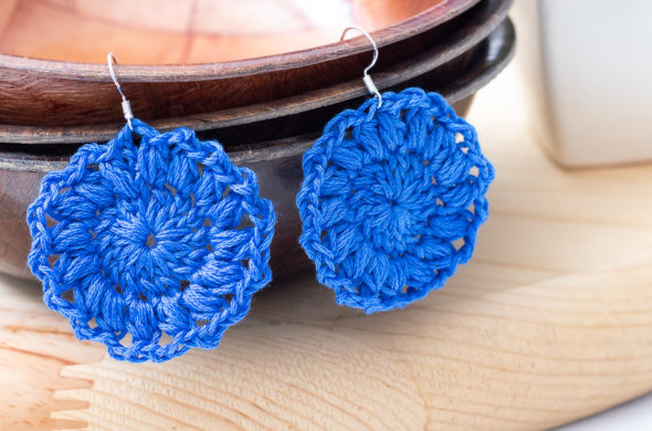 blue crocheted earrings hanging on wooden bowls